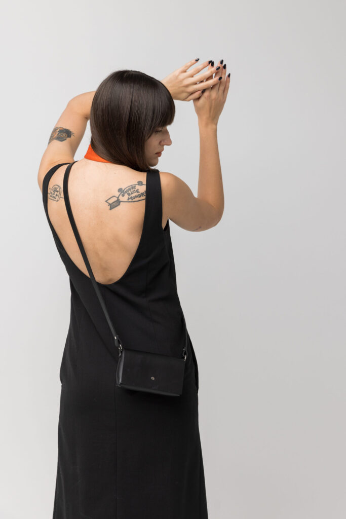 Woman wearing the compact black Kora mini bag across her back.